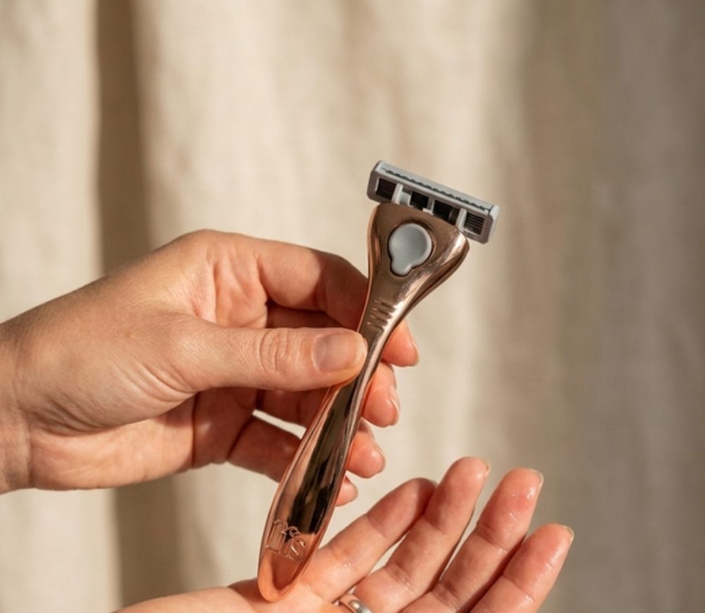 A rose gold FFS razor held between two hands